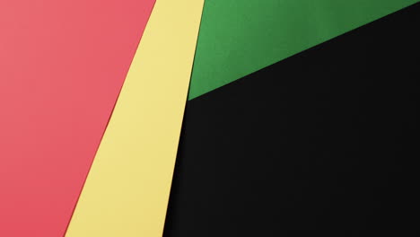 Video-of-red,-yellow-and-green-papers-with-copy-space-on-black-background