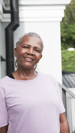 Vertical-video-portrait-of-happy-senior-african-american-woman-smiling-in-garden,-slow-motion