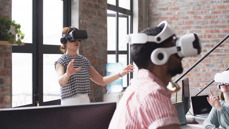 Young-Caucasian-woman-and-Asian-man,-wearing-VR-headsets-as-part-of-a-business-exploration