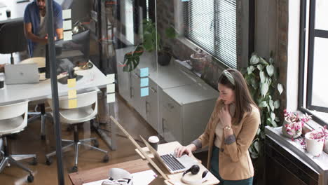 Young-Caucasian-woman-works-at-computer-in-a-modern-office-setting,-handling-her-business-tasks