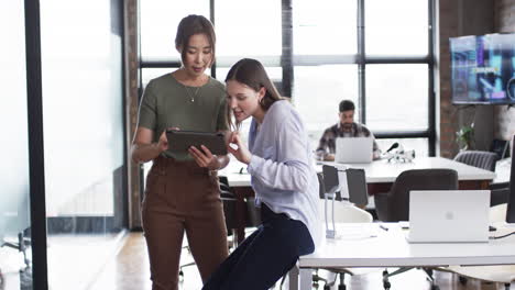 Asian-woman-and-young-Caucasian-woman-review-a-tablet-together-in-a-business-office-setting