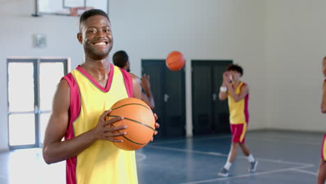 Young-African-American-man-holds-a-basketball-in-a-gym,-with-copy-space