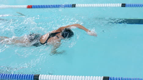 Caucasian-female-swimmer-athlete-swimming-in-a-pool,-with-copy-space