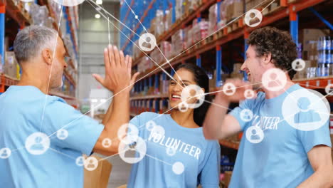 Animation-of-network-of-connections-with-icons-over-diverse-volunteers-working-in-warehouse