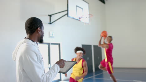 Entrenador-Afroamericano-Entrena-Baloncesto-En-Interiores,-Con-Espacio-Para-Copiar