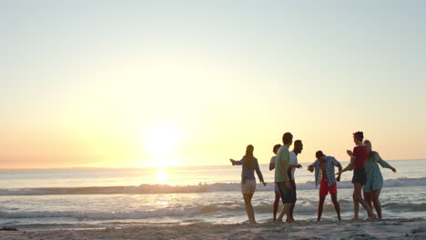 Diverse-friends-enjoy-a-beach-at-sunset,-with-copy-space