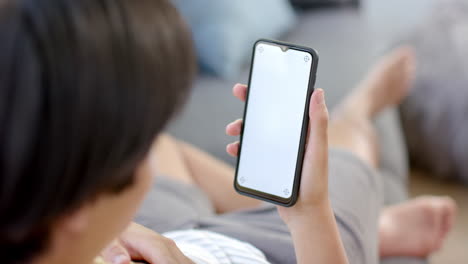 Teenage-Asian-boy-using-a-smartphone-at-home,-with-copy-space