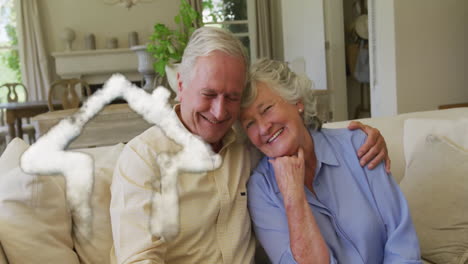 Animation-of-cloud-house-icon-over-happy-senior-caucasian-couple-on-sofa-at-home