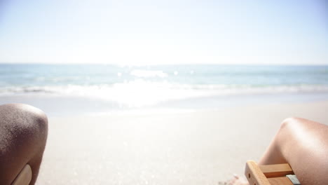 A-young-biracial-man's-arm-extends-towards-the-camera-on-a-sunny-beach-with-copy-space