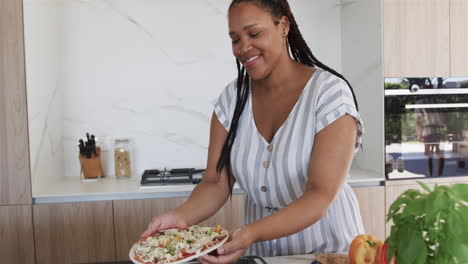 Una-Joven-Birracial-Prepara-Una-Comida,-Incluida-La-Preparación-De-Pizza,-En-Una-Cocina-Casera-Moderna