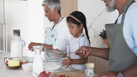 Familia-Birracial-Cocinando-Juntos-En-Una-Cocina-Luminosa,-Con-Un-Niño-Aprendiendo-A-Batir