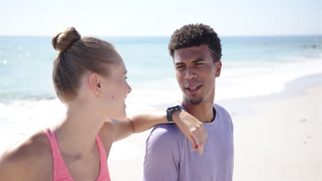 Young-Caucasian-woman-and-biracial-man-share-a-joyful-moment-on-a-sunny-beach