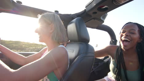 Young-African-American-woman-and-young-Caucasian-woman-enjoy-a-sunny-car-ride-on-a-road-trip