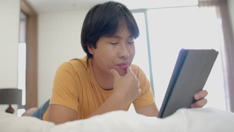 Adolescente-Asiático-Centrado-En-Una-Tableta-En-Casa