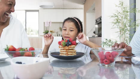 Ein-Kind-Gemischter-Abstammung-Bewundert-Einen-Stapel-Pfannkuchen-Mit-Beeren-An-Einem-Küchentisch