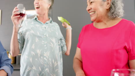 Caucasian-woman-and-senior-biracial-woman-share-a-joyful-moment-with-drinks-and-snacks