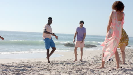 Young-adults-enjoy-a-game-of-soccer-on-the-beach,-with-copy-space