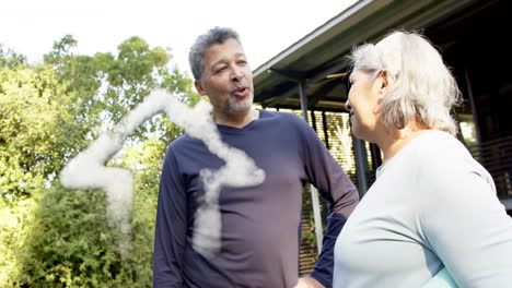 Animation-of-cloud-house-icon-over-happy-diverse-couple-talking-in-garden