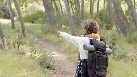 Young-biracial-woman-points-something-out-to-her-friend-during-a-hike,-with-copy-space