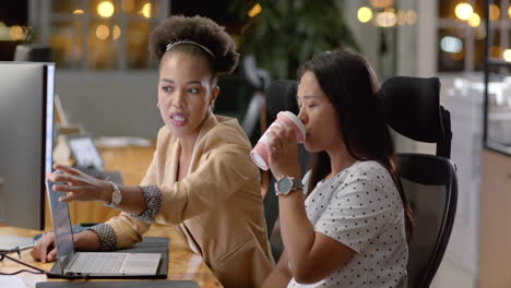 Young-African-American-woman-and-biracial-woman-collaborate-in-a-business-office