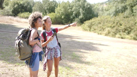 Zwei-Junge-Frauen-Wandern,-Eine-Zeigt-Eine-Richtung-Mit-Kopierraum