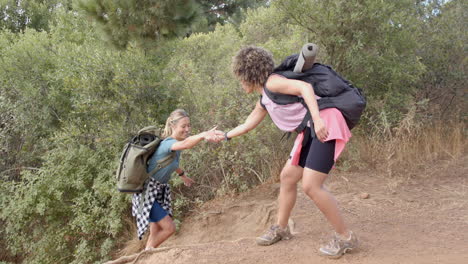 Una-Joven-Caucásica-Ayuda-A-Su-Amiga-Birracial-A-Subir-Por-Un-Sendero-Empinado