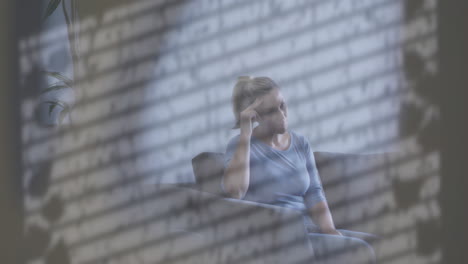 Animation-of-shadow-of-window-blind-and-water-droplets-over-unhappy-caucasian-woman-sitting-at-home