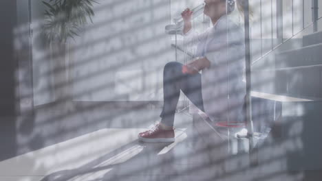 Animation-of-rain-on-window-over-unhappy-caucasian-female-doctor-sitting-on-stairs-in-hospital