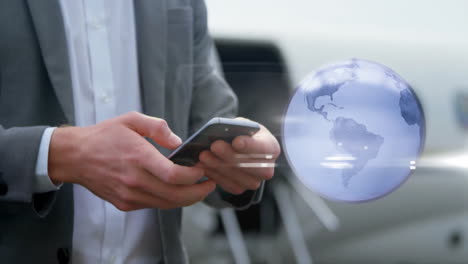 Animación-De-Un-Globo-Giratorio-Sobre-Un-Hombre-De-Negocios-Caucásico-Usando-Un-Teléfono-Inteligente-En-El-Aeropuerto