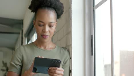 A-young-African-American-woman-browses-her-tablet-by-a-window