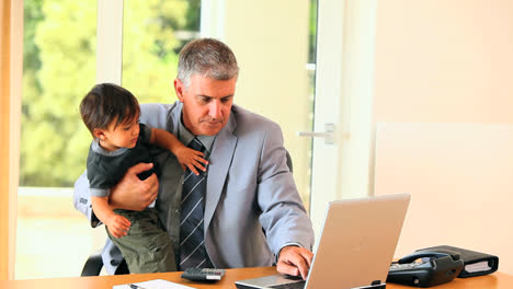 Hombre-De-Traje-Cuidando-Al-Bebé-Y-Tratando-De-Hacer-Trabajo-De-Oficina