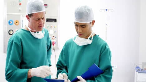 Male-surgeons-discussing-over-medical-reports