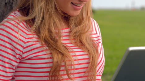 Smiling-woman-using-laptop-at-the-park