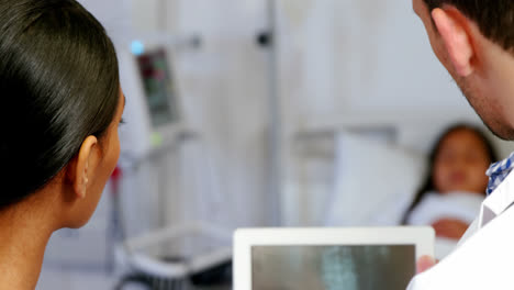 Doctor-and-nurse-looking-at-x-ray-report-on-digital-tablet