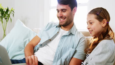 Father-and-daughter-using-laptop-in-living-room