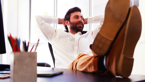 Male-executive-sitting-with-legs-on-table