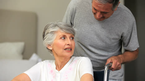 Man-talking-with-his-greyhaired-wife-in-a-wheelchair