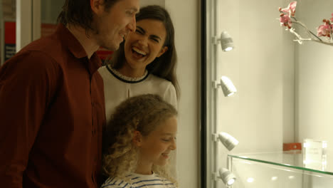 Cute-girl-showing-window-shopping-to-her-parents-