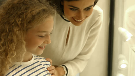 Mother-and-daughter-discussing-in-front-of-window-shopping-