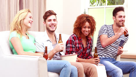 Amigos-Sonrientes-Viendo-Televisión-Mientras-Comen-Palomitas-De-Maíz-Y-Beben-Cerveza