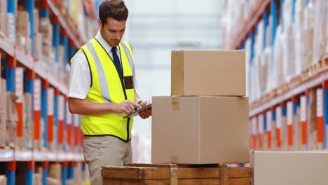 Warehouse-worker-using-digital-tablet-while-checking-packages