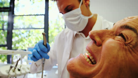 Dentist-examining-a-male-patient-with-tools