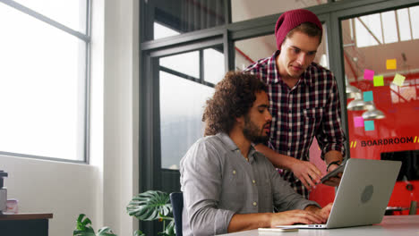 Business-executives-discussing-over-laptop