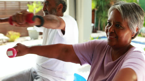 Senior-couple-exercising-with-dumbbell-at-home