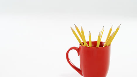 Yellow-color-pencils-kept-in-red-mug-on-white-background