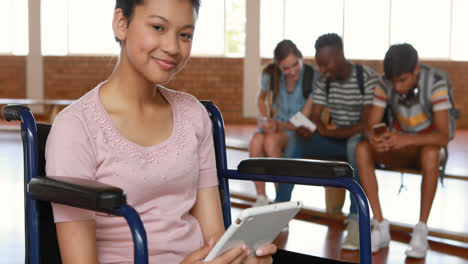 Disabled-schoolgirl-using-digital-tablet-with-classmates-in-background