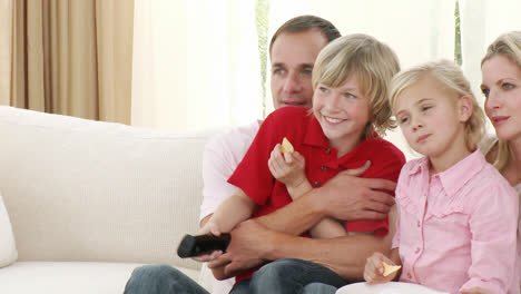 Familia-Viendo-Televisión-Y-Comiendo-Patatas-Fritas-En-Casa