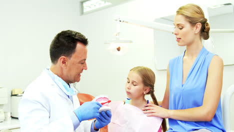 Dentista-Mostrando-A-Un-Paciente-Joven-Cómo-Cepillarse-Los-Dientes