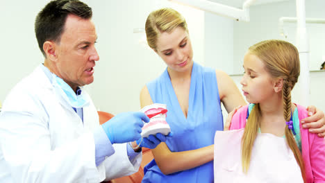 Dentista-Mostrando-A-Un-Paciente-Joven-Cómo-Cepillarse-Los-Dientes