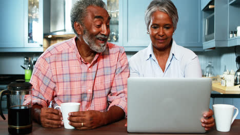 Pareja-Mayor-Usando-Una-Computadora-Portátil-En-La-Cocina